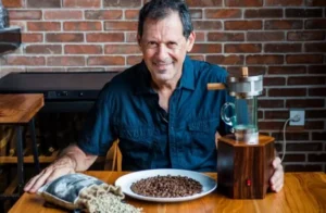 Picture of Asher Yaron with Power Roaster with before and after coffee beans.